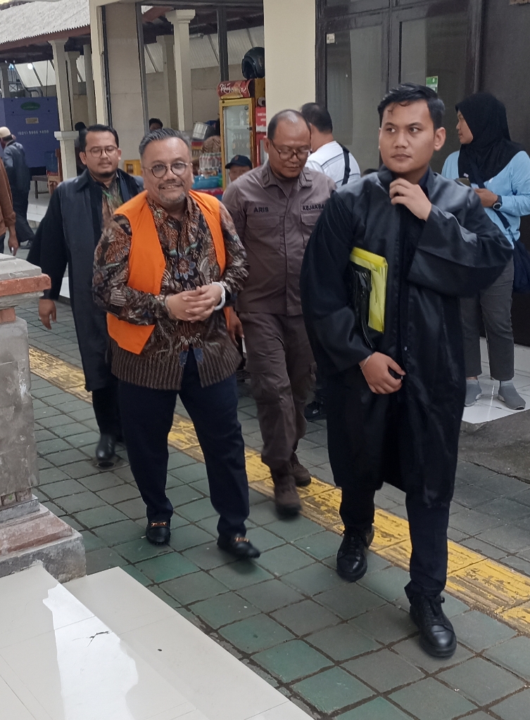 MENUJU RUANG SIDANG: Togar Situmorang (rompi oranye) dibawa ke ruang sidang oleh pengawal tahanan didampingi pengacaranya, Kamis (13/11/2025).