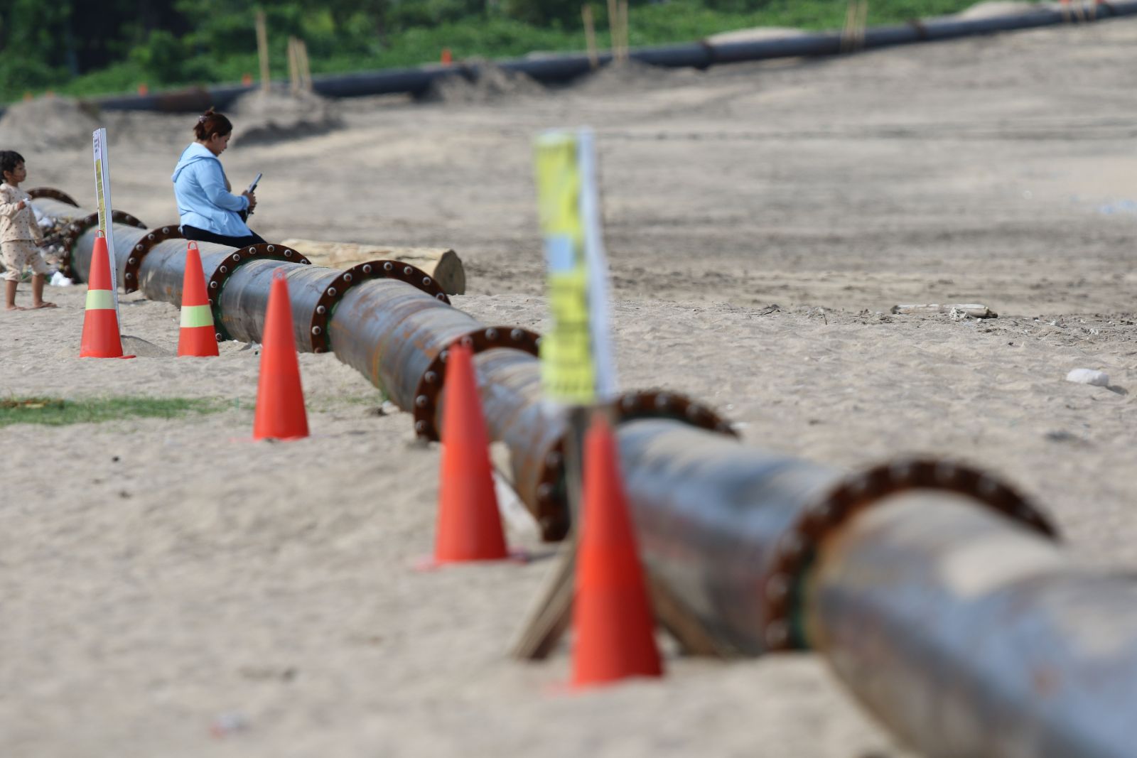 BUKAN PIPA AIR: Seorang warga duduk di pipa penyalur pasir Bali Beach Conservation Project (BBCP) Phase II yg sudah tersambung di Pantai Jerman