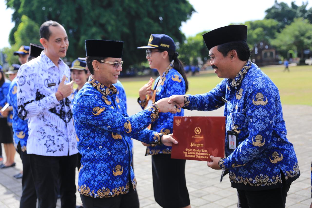 Bupati Klungkung I Made Satria menyerahkan piagam saat Hari Ulang Tahun Korpri ke-54 di Alun-Alun Ida Dewa Agung Jambe, Senin, (1/12/2025).