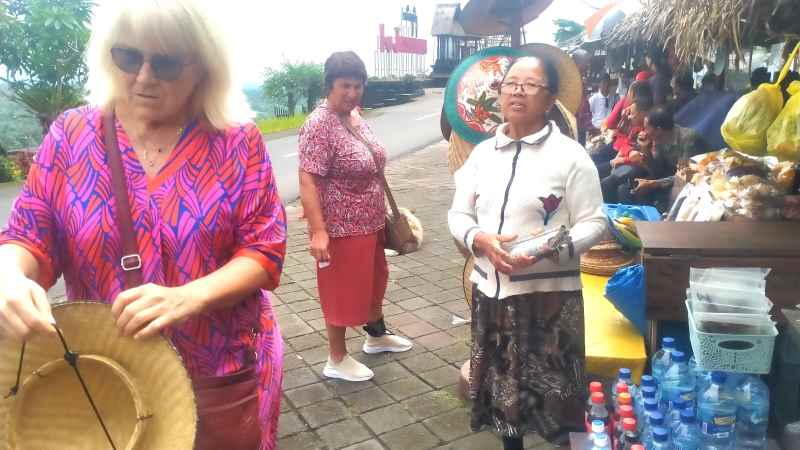 PEKERJA KERAS : Ni Wayan Suarni (kanan) yang berjualan makanan ringan  di Jatiluwih, Penebel, Tabanan, sedang bercakap dengan turis asing. (juliadi/radar bali)