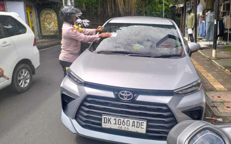BANYAK YANG BANDEL : Kendaraan yang tidak tertib parkir dipasangi stiker oleh petugas gabungan dari Polsek, Dishub Gianyar dan pecalang adat Padangtegal.(foto:Dok.Polsek Ubud,Gianyar)