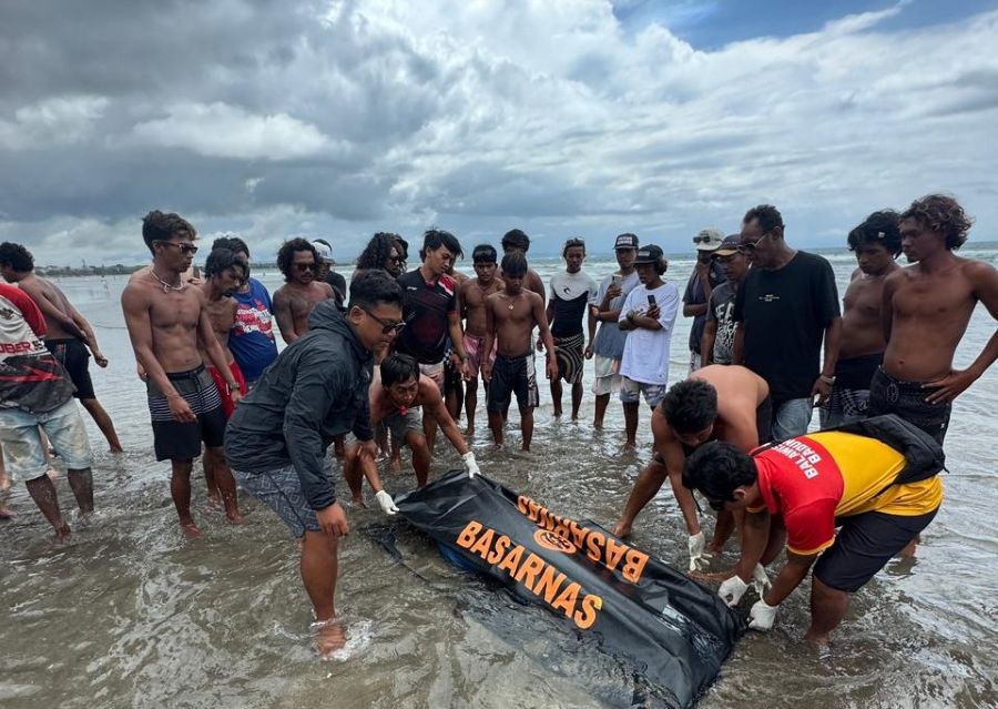 EVAKUASi: Petugas Basarnas dan warga evakjuasi jenazah wanita di Pantai Kuta