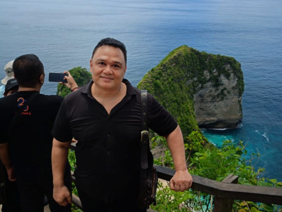 MASIH POLEMIK: Seorang wisatawan asing mengabadikan keindahan pantai Kelingling di Nusa Penida Klungkung yang berbentuk kepala hewan purba Dinosaurus