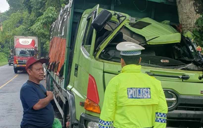 PETAKA DI TENGAH HUJAN: Kondisi truk tronton bermuatan keramik yang alami kecelakaan tunggal menghantam pohon perindang di Jalan Denpasar-Gilimanuk. (Istimewa)