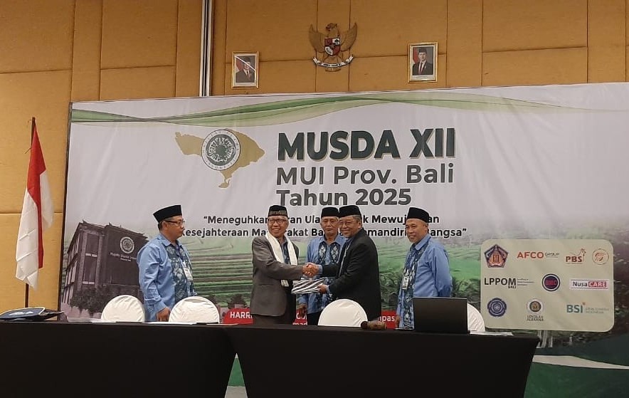LANJUTKAN!: Ketua MUI Bali terpilih, KH. Mahrusun Hadyono (bersurban) menerima dokumen hasil Musda dari pimpinan sidang pleno Totok Nugroho di Harris Cokro, Ahad (14/12/2025)