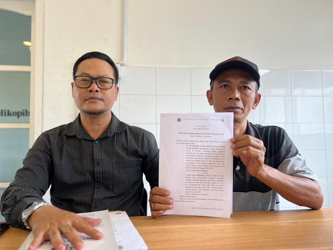BERTAHUN-TAHUN MENANTI: I Gusti Putu Mudiasa (kanan) bersama penasihat hukumnya, Dewa Agus Satrya Wijaya menunjukkan putusan yang memenangkan dirinya atas PLN Rayon Negara
