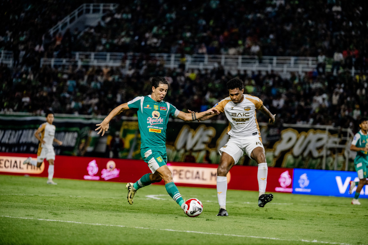 Gelandang Persebaya Bruno Moreira berupaya melewati hadangan bek tengah Dewa United Brian Fatari dalam laga di Stadion GBT. Kedua tim berbagi poin setelah bermain imbang 1-1.