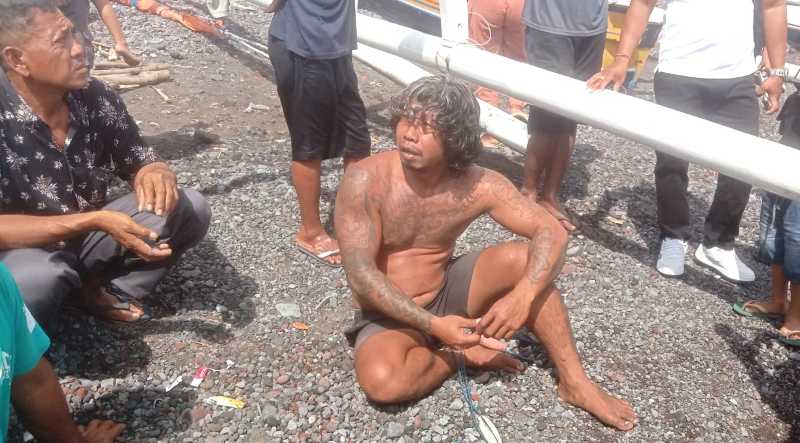 DRAMATIS : Nelayan I Ketut Astika saat berada di bibir pantai usai mengalami musibah jukung miliknya ditabrak kapal jenis tug boat saat mencari ikan di perairan Tulamben. (ist)