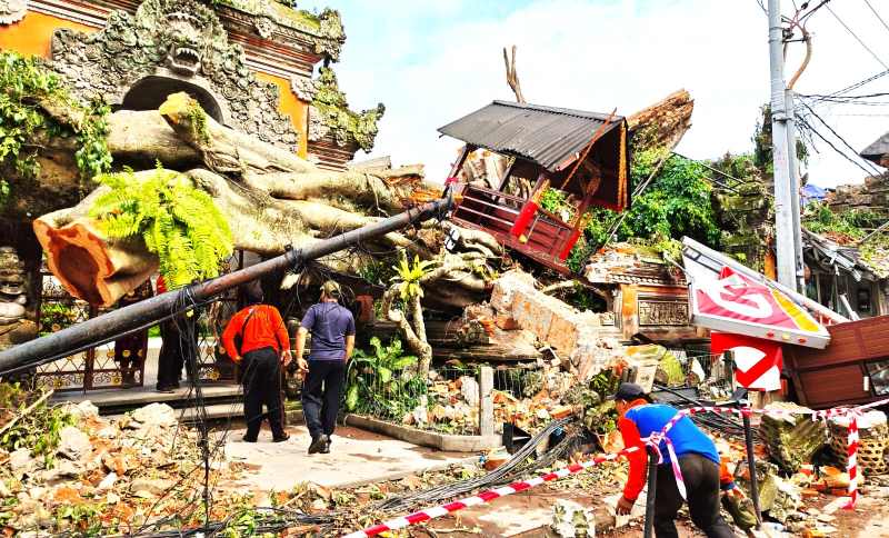 PERLU KERJA EKSTRA : Petugas BPBD Gianyar menyingkirkan dahan pohon yang menimpa bangunan. (foto: BPBD Gianyar)