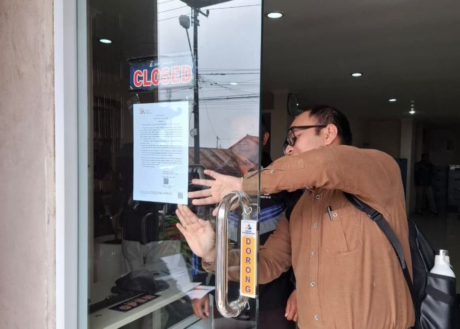 Petugas OJK saat menempel pengumuman pencabutan izin BPR Kamadana, Kintamani, Bangli