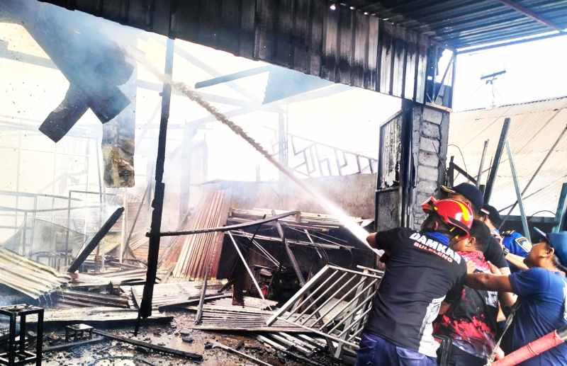 PADAMKAN API : Petugas memadamkan bengkel las yang terbakar di pinggir Jalan Raya Bubunan, Desa Bubunan, Seririt, Buleleng.( Foto: Dinas Damkarmat Buleleng)