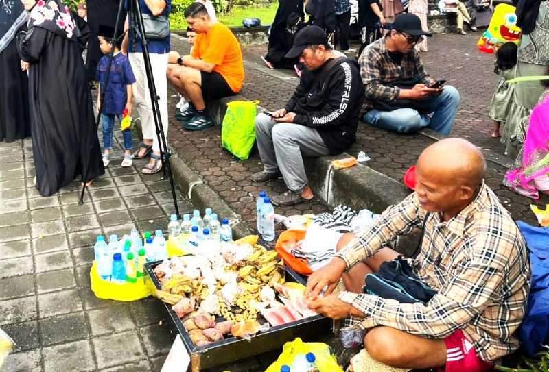 REZEKI LEBARAN : Pak Wayan berjualan aneka camilan dan kopi di Lapangan Renon dan bisa berjualan dua kali. (Muhammad Fajar Bagaskara untuk Radar Bali)