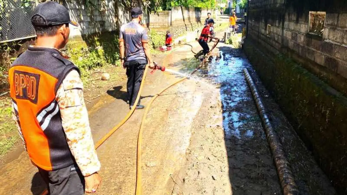 BERSIH-BERSIH LINGKUNGAN : Petugas BPBD Jembrana bersama warga membersihkan sisa-sisa material dan sampah di aliran sungai . (foto: BPBD Jembrana)