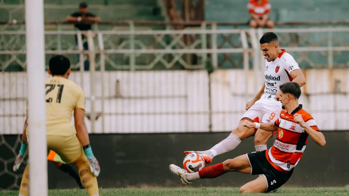 Striker Bali United Boris Kopitovic mencoba melepaskan kawalan ketat lini belakang Madura United dalam laga yang berakhir dengan kemenangan 2-0 untuk tuan rumah.