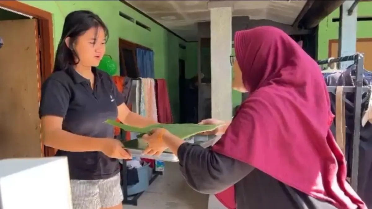 BERBAGI: Siti Aisyah (kanan) Warga LDII Tabanan menyerahkan gulai kambing kepada umat Hindu yang ada di Banjar Malkangin, Tabanan, Rabu (27/5/2026). 
