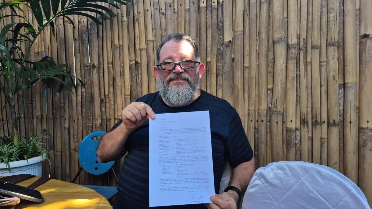 BERDAMAI: Warga negara Amerika Serikat, Scott Bennet Trout, 63, memegang dan menunjukkan surat perdamaian. (andre sulla/radarbali.id)