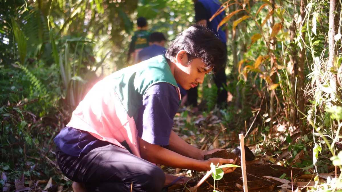 Proses penanaman bibit pohon nangka dan beringin di Banjar Liligundi, Desa Bebandem oleh mahasiswa KKN-PPM Universitas Gadjah Mada dan Universitas Warmadewa.