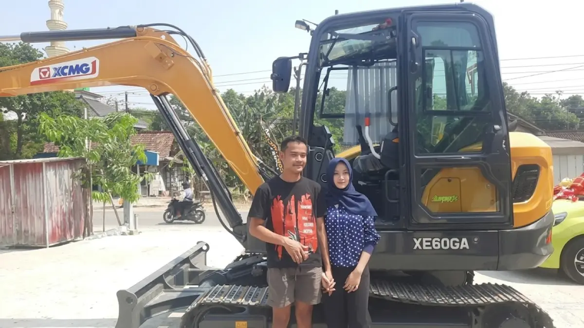 Rico dan Laela di depan ekskavator yang menjadi mahar perkawinan mereka. Selain alat berat tersebut, Riko juga memberikan dua mobil dan dua motor. (Intan Maylani Sabrina/Radar Kudus)