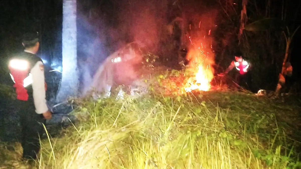 PADAMKAN API : Petugas melakukan pemadaman api yang membakar lahan. (Foto Polsek Melaya, Jembrana)