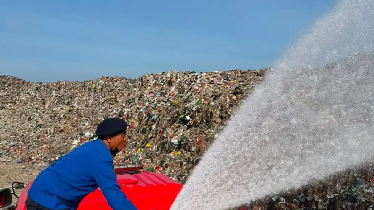 CEGAH KEBAKARAN: Petugas dari Dinas Pemadam Kebakaran dan Penyelamatan Kota Denpasar menyemprotkan air dengan kendaraan Damkar ke gunungan sampah TPA Suwung Senin 24 Agustus 2026. (ist/radarbali.id)