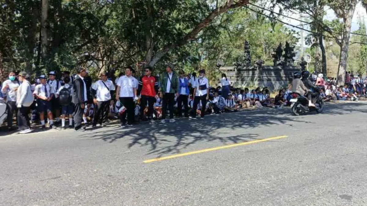 MENUNGGU PRESIDEN : Warga berkumpul di pinggir jalan sambut Presiden Prabowo Subianto. (M.Basir)