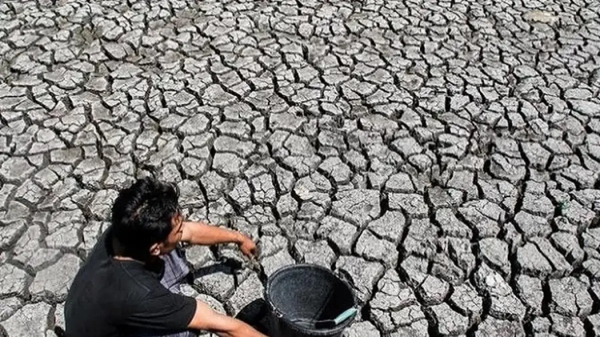 KERING: Seorang warga tengah menunggu mendapat giliran ambil air di sumur akibat kekeringan yang ekstrem.