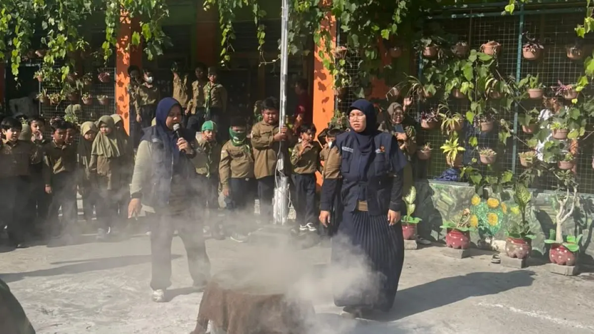 CARA PADAMKAN API: Simulasi cara memadamkan api dengan memakai karung goni basah yang di demonstrasikan oleh Ibu Rosa di depan siswa-siswi SD Muhammadiyah 4 Denpasar Sabtu (26/9/2026). (ist/radarbali.id)