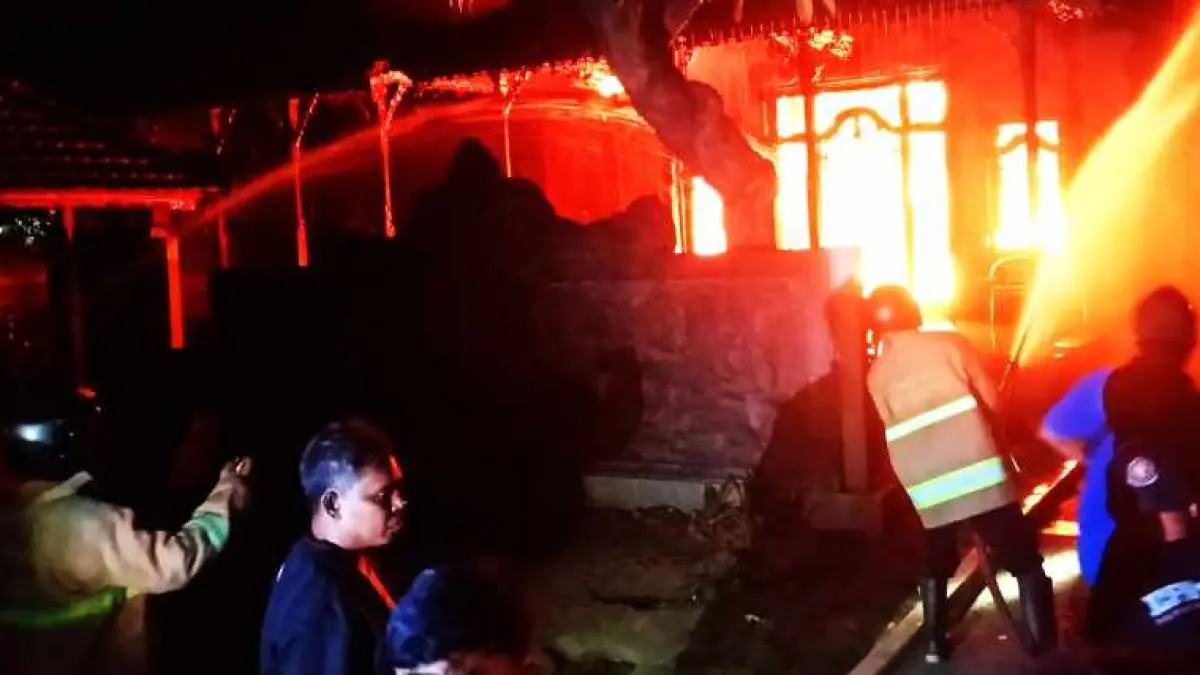 API MENGAMUK : Api membakar rumah milik almarhum Pak Kajar, berusaha dijinakkan oleh petugas.(foto: Foto: Polres Buleleng)