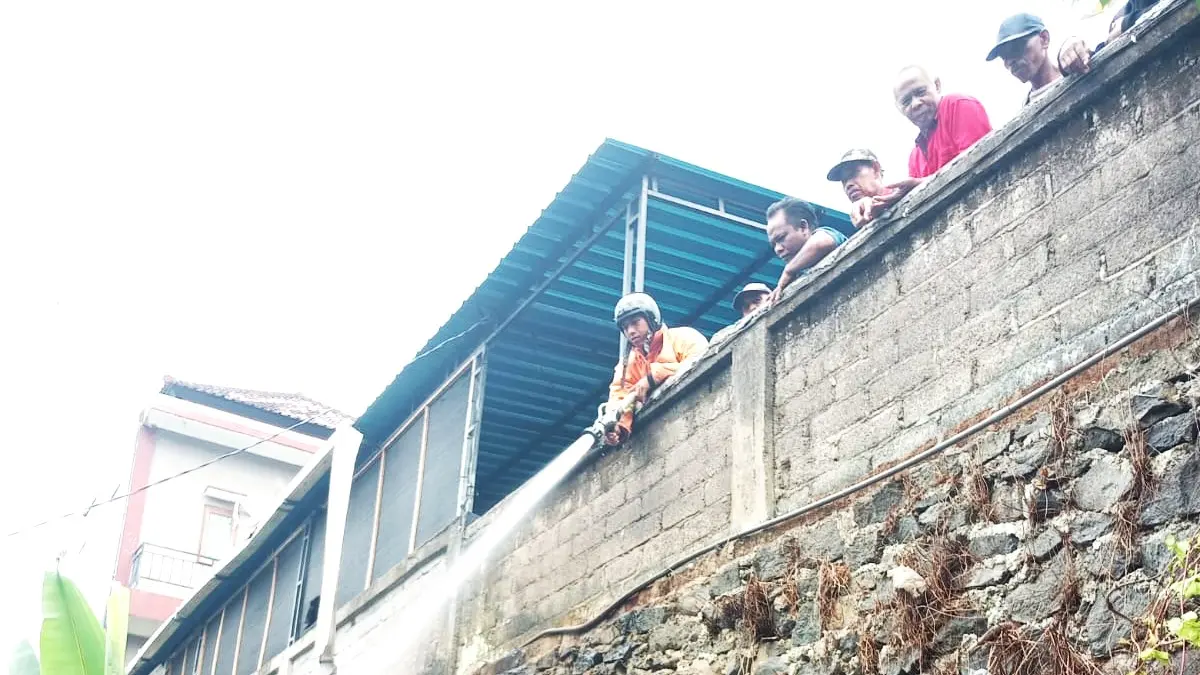 PADAMKAN API : Petugas Damkar memadamkan kobaran api dari tumpukan serabut kelapa. (foto: Damkar Jembrana)