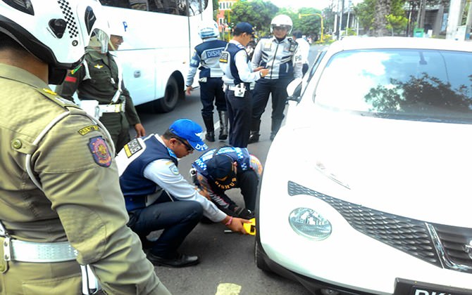 Ilustrasi: petugas menggebok roda mobil yang parkir sembarangan di badan jalan. (dok radarbali.id)