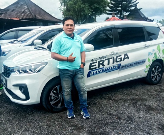 KETAGIHAN: Made Sukamara, dari Jawa Pos Radar Bali berpose di sela-sela media test drive All New Suzuki Ertiga Hyabrid regional Bali yang digelar PT Sejahtera Indobali Trada (Dealer Suzuki Mobil, red), Rabu (7/9).  (IST)