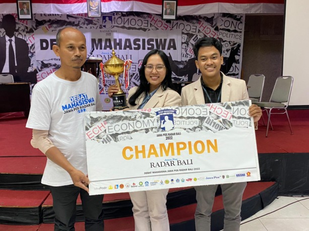 SANG JUARA: Tim debat Politeknik Negeri Bali berpose bersama Pimred Radar Bali Djoko Heru Setiyawan (kiri) di Aula ITB Stikom Bali, Denpasar, Minggu (25/9/2022).