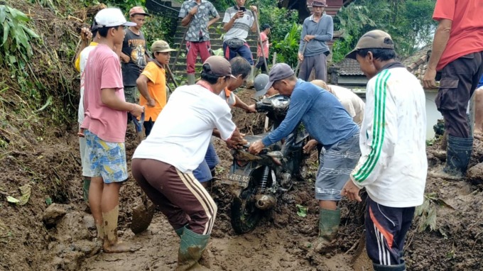 WASPADA: Masyarakat saat melakukan evakuasi terhadap tiga unit sepeda motor milik warga di Banjar Benekasa, Desa Muncan, Kecamatan Selat akibat tertimbun material longsor, Sabtu (8/10).