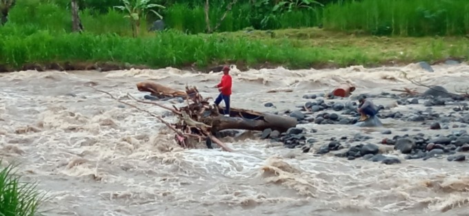 NAHAS DI PERJALANAN : Dua warga Jember terjebak di tengah derasnya aliran sungai Tukad Unda di Banjar Dinas Tangkup, Desa Tangkup Kecamatan Sidemen, Kamis (24/11). (foto:istimewa)