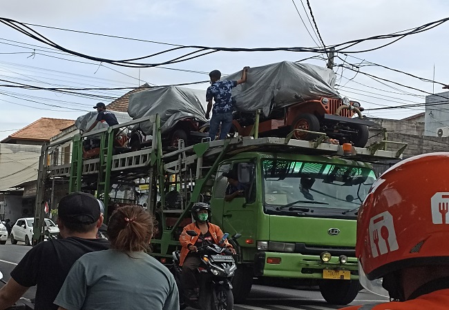Kernet truk mengatur jaringan kabel listrik yang tersangkut truk di kawasan Jalan Raya Sesetan, Denpasar Selatan. (ADRIAN SUWANTO)