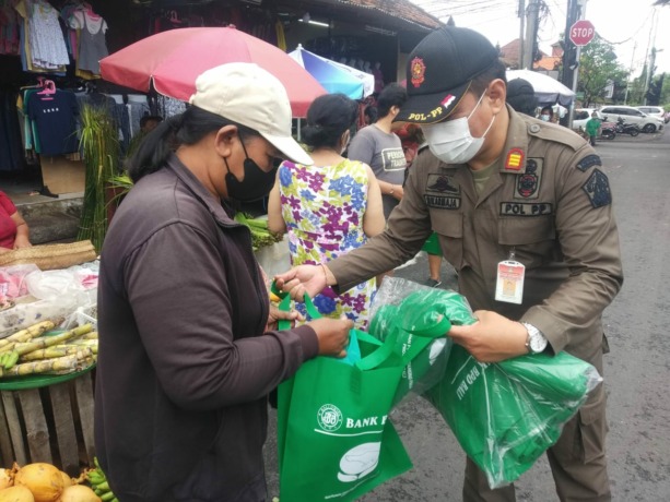 PENCITRAAN?: Aparat Satpol PP Provinsi Bali membagikan bingkisan kepada warga di sejumlah ruas jalan.