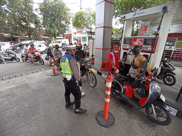AWASI: Polisi terlihat berjaga mengawasi antrean di sejumlah SPBU di Kota Denpasar menyusul kelangkaan bahan bakar minyak jenis solar dan pertalite. (Foto: Adrian Suwanto/radar bali)