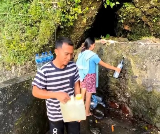 TAK SESUAI: Salah seorang warga asal Banjar Dinas Tangkup Anyar, Desa Tangkup Kecamatan Sidemen saat mencari air di salah satu sumber air di desa tersebut akibat air PDAM mati sejak empat bulan lalu.