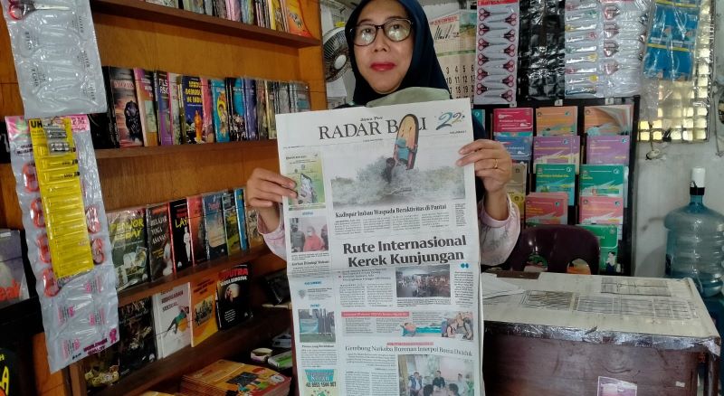TETAP OPTIMISTIS : Bu Tutik, salah seorang  penjual koran di Toko Surya Jalan Gajah Mada, Tabanan, ini tetap optimistis bertahan. (foto:juliadi/radar bali)