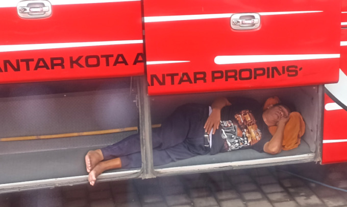 NIKMAT ITU SEDERHANA: Awak bus Gunung Harta asyik tidur di bagasi. (adrian suwanto/radar bali)