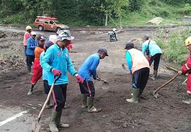 Petugas gotong royong membersihkan material yang menutup badan jalan di Banjar Pemuteran, Desa Pempatan, Kecamatan Rendang, Sabtu (25/2). (foto ist)