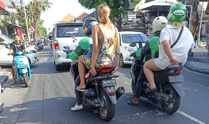 CONTOH BURUK : Seorang pengojek online dengan motor bernomor polisi tidak meminjamkan helm kepada penumpang yang diboncengnya. (foto:adriansuwanto/radar bali)