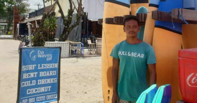 BAGI PENGGEMAR OLAHRAGA EKSTREM: Yusuf Situmorang saat melayani turis yang akan bermain selancar di Pantai Seminyak, Badung beberapa hari lalu. (ni kadek novi febriani/radar bali)