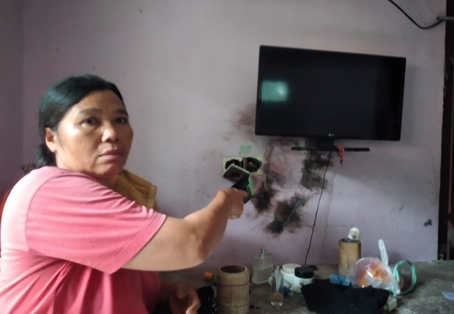 Ni Made Sari saat menunjukkan televisi miliknya yang hangus terbakar akibat sambaran petir yang terjadi pada Selasa sore (4/4) kemarin. (foto Ist)