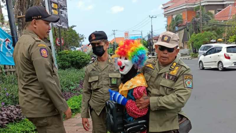 DITANGKAP : Badut yang sedang beraksi di perempatan lampu merah Jalan Raya Gatsu Barat-Buluh Indah ini ditangkap Satpol PP.(foto:  adrian suwanto/radar bali)