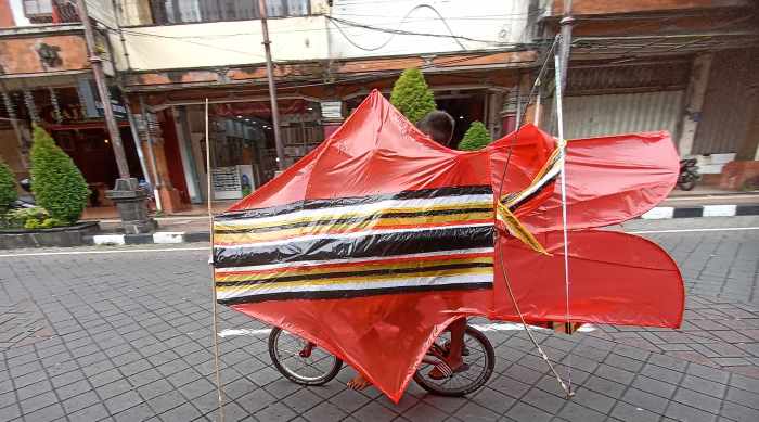 GEDE LAYANGANNYA DARIPADA ORANGNYA: Seorang bocah membawa layangan melintasi Jalan Gajah Mada, Denpasar. (adrian suwanto/radar bali)