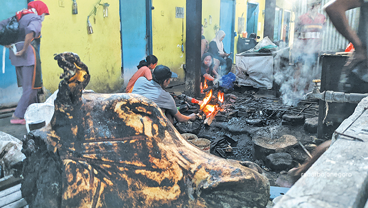 MENGHADAPI PANAS: Zaenuri beserta lima pekerja membuka jasa bakar bulu kepala dan kaki sapi kambing. Kemarin aktivitasnya di Pasar Kota Bojonegoro itu ramai. (DHANI WAHYU ALFIANSYAH/RDR.BJN)