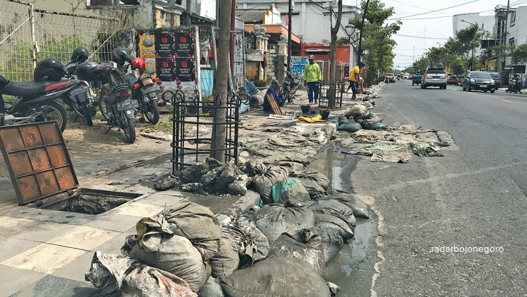 CEGAH GENANGAN: Pekerja tampak membersihkan drainase kota. Angkut material sedimen di dalam drainase dengan sak-sak. (BHAGAS DANI PURWOKO/RDR.BJN)