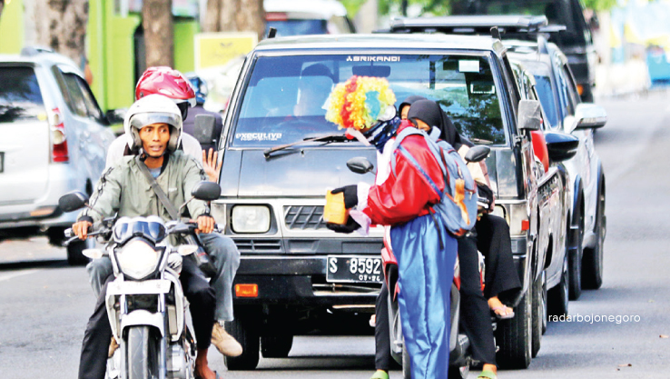 PERLU PEMBINAAN: Pengemis berpakaian badut saat meminta-minta di traffic light di pusat Lamongan kota. (ANJAR DWI PRADIPTA/RDR.LMG)