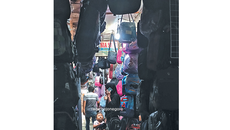 MULAI DICARI: Salah satu pembeli memilih sepatu hitam di salah satu toko. Tampak deretan tas di stan Pasar Kota Bojonegoro. (BHAGAS DHANI PURWOKO/RDR.BJN)